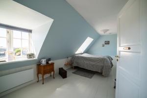 a bedroom with blue walls and a bed and a window at Mandø Kro in Ribe