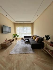 un salon avec un canapé noir et une table dans l'établissement Shems Bouznika, à Bouznika