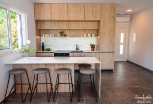 a kitchen with wooden cabinets and bar stools at Modern two bedroom seafront oasis in Skrivena Luka +21 photos