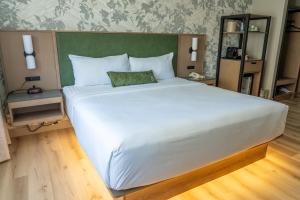 a large white bed with a green headboard in a room at Park Town Hotel in Saskatoon