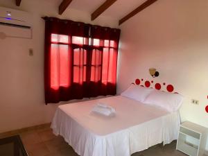 ein Schlafzimmer mit einem weißen Bett und einem roten Fenster in der Unterkunft Casa de campo en Buena Vista - A una cuadra de la plaza in Buena Vista