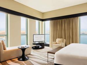 Una habitación de hotel con una cama, un televisor y ventanas. en Sofitel Abu Dhabi Corniche, en Abu Dabi