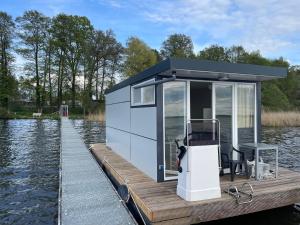 a small cabin on a dock on a body of water at Hausboot Schwielochsee classic in Schwielochsee