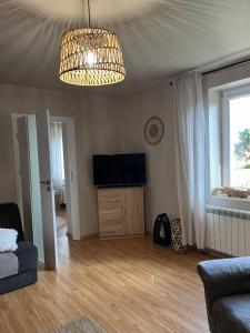 a living room with a television and a chandelier at Agroturystyka Smulsko in Przykona +12 photos