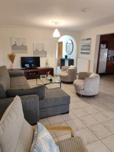 a living room with couches and chairs and a tv at SOLMAR HOUSE in Flogita