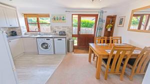 a kitchen and dining room with a table and a washing machine at Cockleshell Croyde Sleeps 4 By the Seaside in Croyde