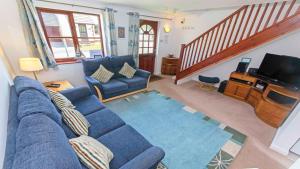 a living room with a blue couch and a tv at Cockleshell Croyde Sleeps 4 By the Seaside in Croyde