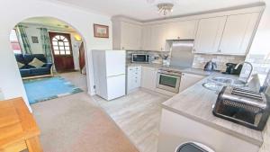 a kitchen with white appliances and a living room at Cockleshell Croyde Sleeps 4 By the Seaside in Croyde