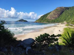 a beach with people on the sand and the ocean at Pousada da Tia Penha in Engenho Novo