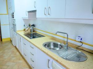 Una cocina con fregadero de acero inoxidable y gabinetes blancos. en Puerta Romana, en Carmona 40 fotos más