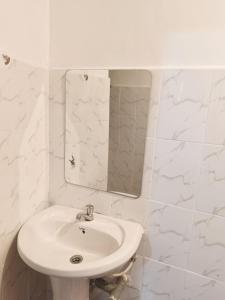 a white bathroom with a sink and a mirror at Modern Stay Ruaka in Ruaka +3 photos