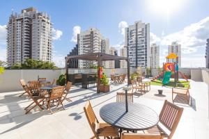 a patio with tables and chairs and a playground at Sou Ecoville in Curitiba