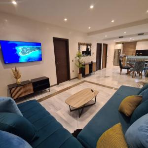 un salon avec un canapé bleu et une télévision dans l'établissement Appartement sur la corniche 2 chambres, à Tanger