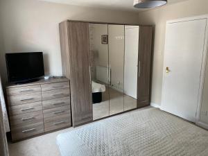 a bedroom with a dresser with a television and a mirror at Impala Apartment in Wick