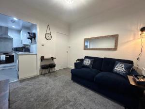 a living room with a blue couch and a kitchen at 'Nautical Nook' -Island Escape in Millport