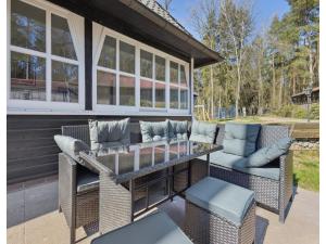 a patio with a glass table and wicker chairs at Ferienhaus, Schneverdingen in Schneverdingen