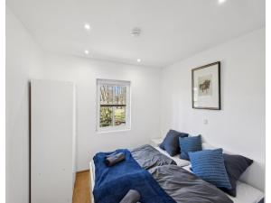 a white bedroom with a bed and blue pillows at Ferienhaus, Schneverdingen in Schneverdingen