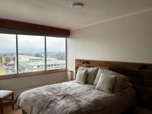 a bedroom with a bed with a large window at Edificio Guadalauquen in Valdivia