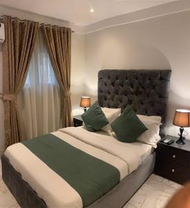 a bedroom with a large bed with green pillows at Wellaton Suites in Abuja