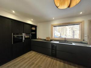a large kitchen with black cabinets and a window at Chalet N°5 - CHALET PRESTIGE 9 P. PROCHE PISTES-Tout inclus MAE-4253 in Vars