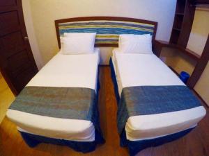 two beds in a room with wooden floors at Golden Gate Suites in Dumaguete