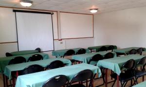 una clase con mesas verdes y sillas y una pizarra en Hotel Marsal, en Antofagasta
