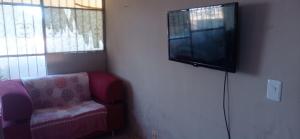 uma sala de estar com uma cadeira e uma televisão de ecrã plano em Residencial Barbosa - Apto 301 em Macaé