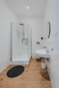 a white bathroom with a shower and a sink at Lesny Dwór w Górach Sowich in Wolibórz +39 photos
