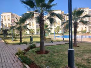 a park with palm trees in front of a building at Appartement 2ch salon 2sdb 75m2 avec piscine in Bouznika
