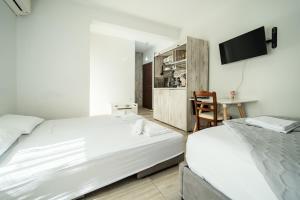 ein Schlafzimmer mit zwei Betten und einem Fernseher an der Wand in der Unterkunft Seaside Studio in Nea Peramos, Sleeps 4 in Néa Péramos