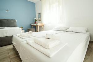 ein weißes Schlafzimmer mit 2 Betten und Handtüchern darauf in der Unterkunft Seaside Studio in Nea Peramos, Sleeps 4 in Néa Péramos