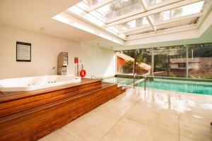 a large bathroom with a tub and a swimming pool at Apto com Piscina Aquecida em Canela in Canela