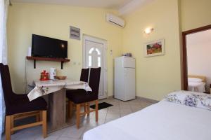 a room with a table and a refrigerator and a bed at Apartments Milena in Stomorska