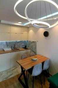 a kitchen with a table and chairs under a large light fixture at Apartman Taris in Vrnjačka Banja