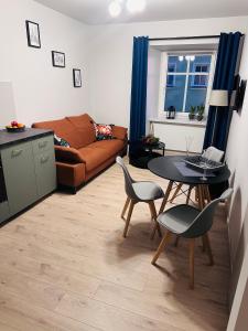 a living room with a couch and a table and chairs at Kobal Apart in Bolesławiec