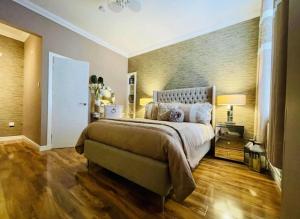 a bedroom with a large bed and a wooden floor at Isle Be Back-Ground Floor Flat in Millport