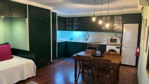 丰沙尔Studio by Casa da Quinta的厨房配有绿色橱柜和桌椅
