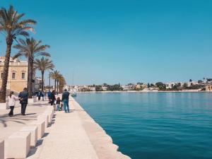 people walking on a sidewalk next to a body of water at Casa Moi in Brindisi