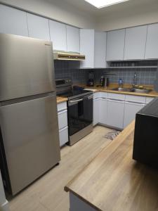 Una cocina con gabinetes blancos y un refrigerador. en Fairview Townhouse, en Vancouver