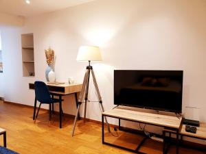 a living room with a television and a table with a lamp at Sadi Carnot - 1B Studio in Millau