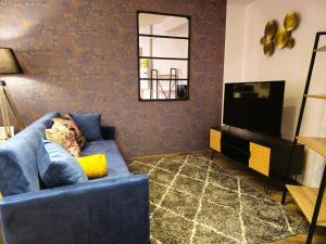 a living room with a blue couch and a tv at Mitrons - Apt A in Saint-Affrique