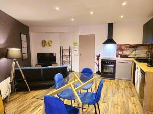 a living room with a glass table and blue chairs at Mitrons - Apt A in Saint-Affrique +6 photos