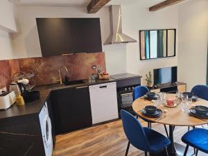a kitchen with a table and blue chairs in a room at Mitrons - 1A in Saint-Affrique