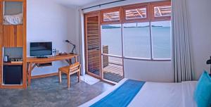 a bedroom with a bed and a desk and a window at Escape Beach Resort - SHA Extra Plus Certified in Mae Nam