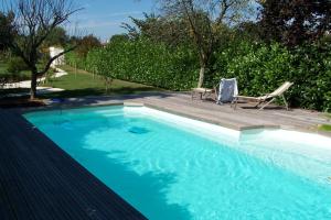 a large blue swimming pool with two lounge chairs at Maison Lépie in Beurlay