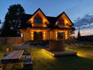 a wooden house with lights on it at night at Hygge Tatra Luxury Chalet - Domki z Balią in Murzasichle