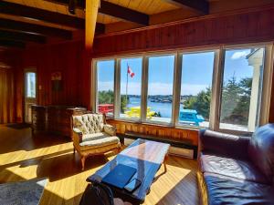 a living room with a couch and a table and windows at 181 Oceanside Inn in Peggy's Cove