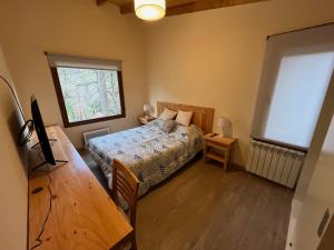 a bedroom with a bed and a table and a window at LOS HUEMULES - casa nueva en medio del bosque y a pasos del centro de la ciudad- in San Carlos de Bariloche