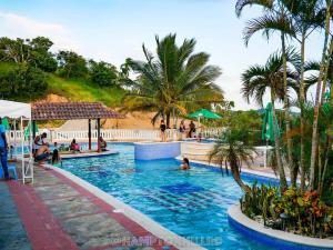 a swimming pool with palm trees and people in it at Hampton Hill La Loma - Escapada Natural, Santiago RD 