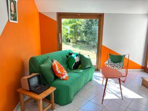 a living room with a green couch and a laptop on a table at Chez Raoul, maison agréable in Villebernier
